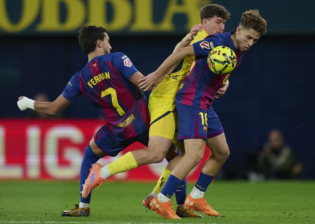 (251222) -- VILA-REAL, Dec. 22, 2025 (Xinhua) -- Pau Navarro (C) of Villarreal vies with Fermin Lopez (R) of Barcelona during the La Liga football match between Villarreal and Barcelona in Vila-Real, Spain, Dec. 21, 2025. (Str/Xinhua)