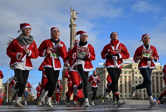 (251222) -- MADRID, Dec. 22, 2025 (Xinhua) -- Runners in Santa Claus costumes attend a Christmas-themed running event in Madrid, Spain, Dec. 21, 2025. (Xinhua/Cheng Min)