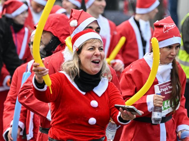 (251222) -- MADRID, Dec. 22, 2025 (Xinhua) -- Runners in Santa Claus costumes attend a Christmas-themed running event in Madrid, Spain, Dec. 21, 2025. (Xinhua/Cheng Min)