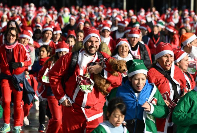 (251222) -- MADRID, Dec. 22, 2025 (Xinhua) -- Runners in Santa Claus costumes attend a Christmas-themed running event in Madrid, Spain, Dec. 21, 2025. (Xinhua/Cheng Min)