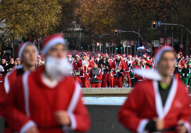 (251222) -- MADRID, Dec. 22, 2025 (Xinhua) -- Runners in Santa Claus costumes attend a Christmas-themed running event in Madrid, Spain, Dec. 21, 2025. (Xinhua/Cheng Min)