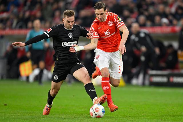 (251222) -- MAINZ, Dec. 22, 2025 (Xinhua) -- Dominik Kohr (R) of FSV Mainz 05 vies with James Sands of FC St. Pauli during the German first division Bundesliga football match between FSV Mainz 05 and FC St. Pauli in Mainz, Germany, Dec. 21, 2025. (Photo by Ulrich Hufnagel/Xinhua)