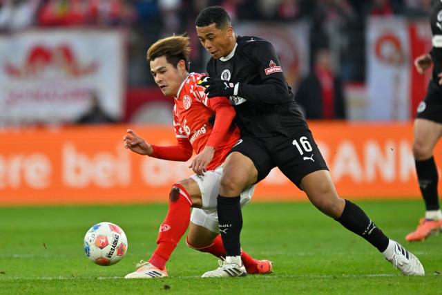 (251222) -- MAINZ, Dec. 22, 2025 (Xinhua) -- Sano Kaishu (L) of FSV Mainz 05 vies with Fujita Joel Chima of FC St. Pauli during the German first division Bundesliga football match between FSV Mainz 05 and FC St. Pauli in Mainz, Germany, Dec. 21, 2025. (Photo by Ulrich Hufnagel/Xinhua)