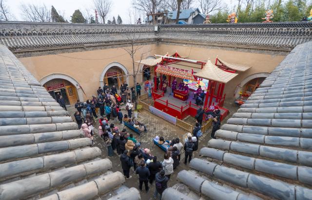 (251222) -- SANMENXIA, Dec. 22, 2025 (Xinhua) -- Tourists watch a local opera performance at a traditional Dikengyuan residence in Beiying Village, Zhangbian Township, Shanzhou District, Sanmenxia City of central China's Henan Province, Dec. 21, 2025.
  The Dikengyuan residence, a traditional residential construction in west Henan featuring a sunken courtyard, is of high value in the study of local history, architecture, geology and sociology. It was listed in the third batch of China's national intangible cultural heritage in 2011.
  In recent years, Sanmenxia has continuously advanced the restoration of these peculiar dwellings, turning them into tourist attractions to further boost development in their neighborhood. (Photo by Zhao Yongtao/Xinhua)
