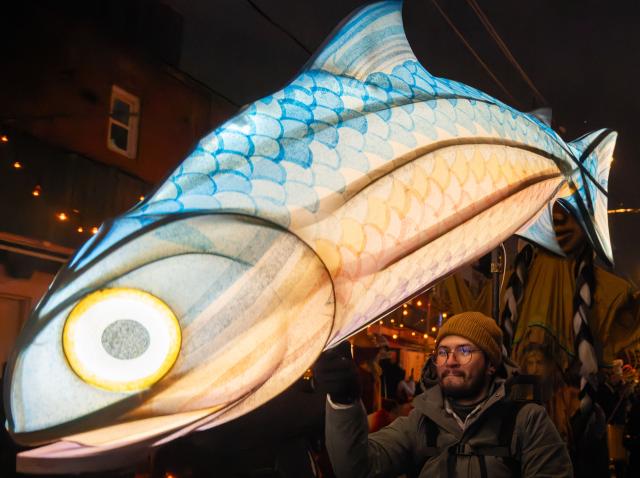 (251222) -- TORONTO, Dec. 22, 2025 (Xinhua) -- A man holding a fish-shaped lantern participates in the 2025 Kensington Market Winter Solstice event in Toronto, Canada, Dec. 21, 2025. The annual event to celebrate the longest night of the year was held here on Sunday. (Photo by Zou Zheng/Xinhua)