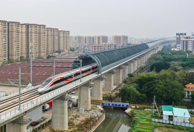 (251222) -- GUANGZHOU, Dec. 22, 2025 (Xinhua) -- A bullet train runs on a section of tracks covered in noise barriers along the Guangzhou-Zhanjiang High-Speed Railway in south China's Guangdong Province, Dec. 22, 2025.
  Spanning approximately 401 kilometers, the Guangzhou-Zhanjiang High-Speed Railway began operation on Monday. With a designed top speed of 350 kilometers per hour, the travel time can be reduced to around one hour and a half between the Guangzhou Baiyun Railway Station and the Zhanjiang North Railway Station, both in Guangdong. (Photo by Li Jiashan/Xinhua)