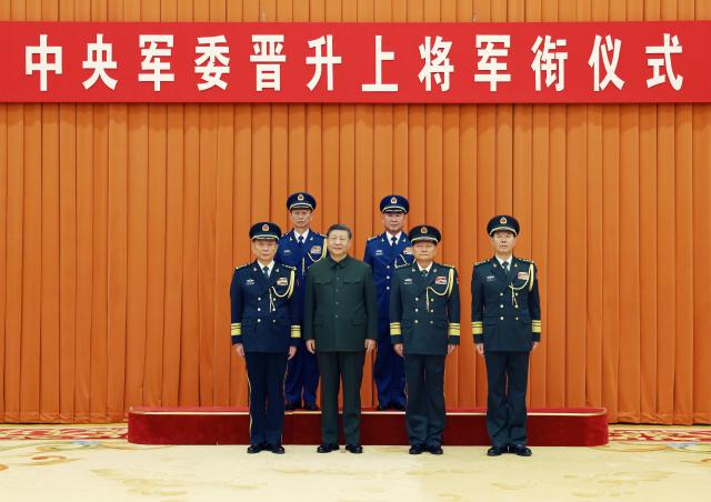 (251222) -- BEIJING, Dec. 22, 2025 (Xinhua) -- Xi Jinping, chairman of the Central Military Commission (CMC), and other leaders pose for a group photo with the promoted military officers in Beijing, capital of China, Dec. 22, 2025. Xi on Monday presented certificates of order to promote two military officers to the rank of general. (Xinhua/Li Gang)