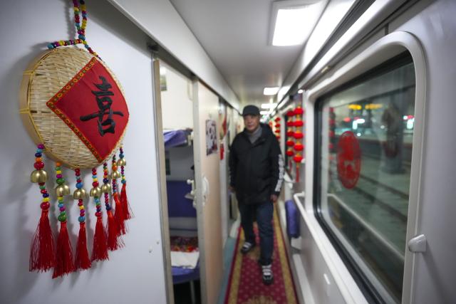 (251222) -- HARBIN, Dec. 22, 2025 (Xinhua) -- A passenger is seen on Train K7041 at Harbin Railway Station in Harbin, northeast China's Heilongjiang Province, on Dec. 22, 2025. Train K7041, the first northeast folk culture-themed train operated this winter, departed from Harbin Railway Station and headed for Mohe City on Monday. (Xinhua/Wang Song)