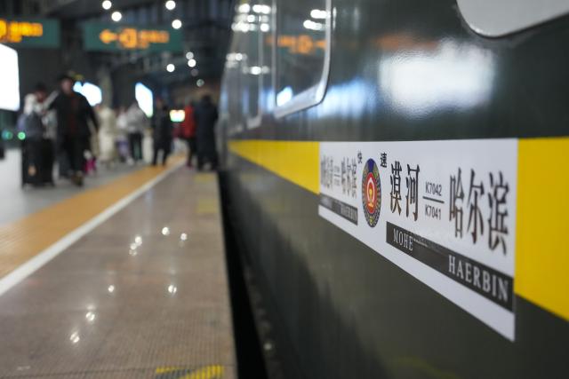 (251222) -- HARBIN, Dec. 22, 2025 (Xinhua) -- Passengers walk past Train K7041 at Harbin Railway Station in Harbin, northeast China's Heilongjiang Province, on Dec. 22, 2025. Train K7041, the first northeast folk culture-themed train operated this winter, departed from Harbin Railway Station and headed for Mohe City on Monday. (Xinhua/Wang Song)