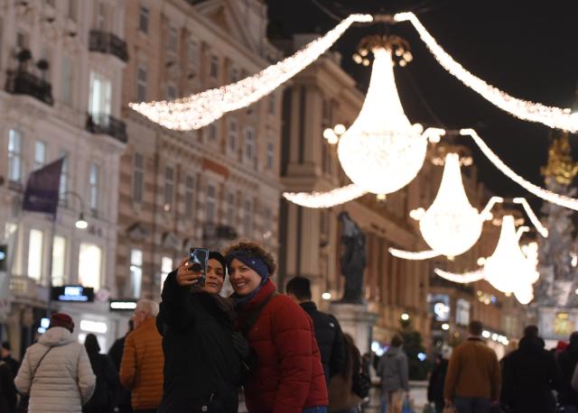 (251222) -- VIENNA, Dec. 22, 2025 (Xinhua) -- People take selfies on a street in Vienna, Austria, Dec. 22, 2025. (Xinhua/He Canling)