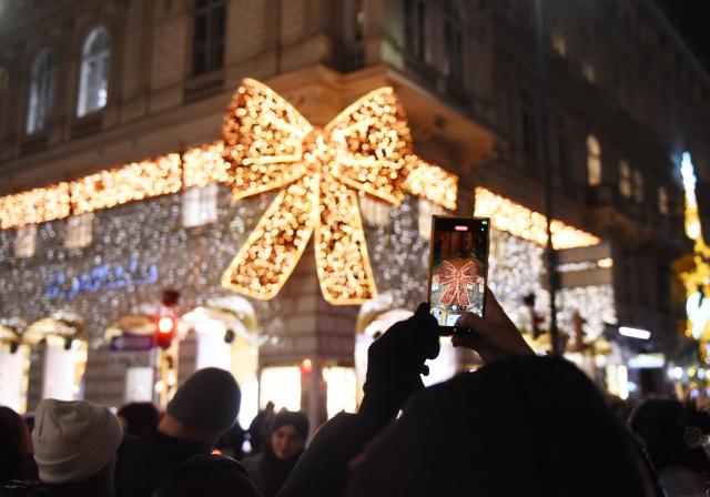 (251222) -- VIENNA, Dec. 22, 2025 (Xinhua) -- People take photo of decorative lights in Vienna, Austria, Dec. 22, 2025. (Xinhua/He Canling)