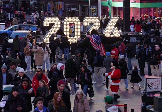 (251223) -- NEW YORK, Dec. 23, 2025 (Xinhua) -- People are seen around a light installation for the upcoming 2026 at Times Square in New York, the United States, Dec. 22, 2025. (Xinhua/Zhang Fengguo)