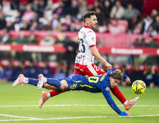 (251223) -- BEIJING, Dec. 23, 2025 (Xinhua) -- Giuliano Simeone (bottom) of Atletico de Madrid vies with Ivan Martin of Girona FC during the La Liga football match between Girona FC and Atletico de Madrid in Montilivi Stadium, Girona, Spain, on Dec. 21, 2025. (Photo by Joan Gosa/Xinhua)