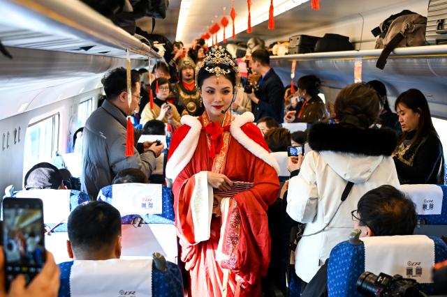 (251223) -- BAOTOU, Dec. 23, 2025 (Xinhua) -- A performer (C) interacts with passengers on bullet train No.D4667, the first train of the Baotou-Yinchuan High-Speed Railway, Dec. 23, 2025. The Baotou-Huinong section of the Baotou-Yinchuan High-Speed Railway was completed and opened to traffic on Tuesday, marking the full-line operation of the railway.
  This railway connects Baotou in north China's Inner Mongolia Autonomous Region with Yinchuan in northwest China's Ningxia Hui Autonomous Region, enhancing the high-speed railway network in northwest China. (Xinhua/Li Zhipeng)