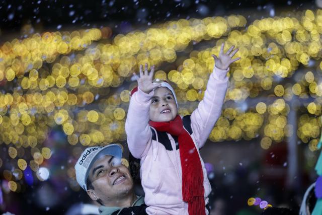 (251223) -- MEXICO CITY, Dec. 23, 2025 (Xinhua) -- A child plays with artificial snow during a winter lights festival at the Zocalo square in Mexico City, Mexico, Dec. 22, 2025. A winter lights festival is held here to welcome the arrival of 2026. (Xinhua/Francisco Canedo)