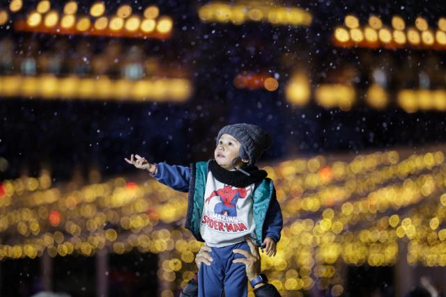 (251223) -- MEXICO CITY, Dec. 23, 2025 (Xinhua) -- A child plays with artificial snow during a winter lights festival at the Zocalo square in Mexico City, Mexico, Dec. 22, 2025. A winter lights festival is held here to welcome the arrival of 2026. (Xinhua/Francisco Canedo)