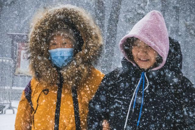 (251223) -- CHANGCHUN, Dec. 23, 2025 (Xinhua) -- People walk amid snow in Changchun, northeast China's Jilin Province, Dec. 23, 2025. Changchun on Tuesday experienced snowfalls due to the impact of a new cold front. (Xinhua/Xu Chang)