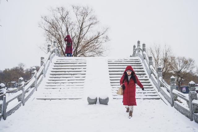 (251223) -- CHANGCHUN, Dec. 23, 2025 (Xinhua) -- People walk amid snow in Changchun, northeast China's Jilin Province, Dec. 23, 2025. Changchun on Tuesday experienced snowfalls due to the impact of a new cold front. (Xinhua/Xu Chang)