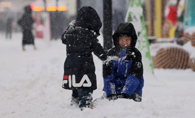 (251223) -- HARBIN, Dec. 23, 2025 (Xinhua) -- Two children play in snow in Harbin, northeast China's Heilongjiang Province, Dec. 23, 2025. The meteorological observatory of Harbin issued a yellow alert for blizzard on Tuesday. (Photo by Zhang Shu/Xinhua)