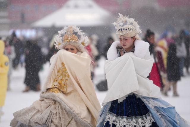 (251223) -- HARBIN, Dec. 23, 2025 (Xinhua) -- Visitors walk in snow at Harbin Architectural Art Square in Harbin, northeast China's Heilongjiang Province, Dec. 23, 2025. The meteorological observatory of Harbin issued a yellow alert for blizzard on Tuesday. (Xinhua/Wang Jianwei)