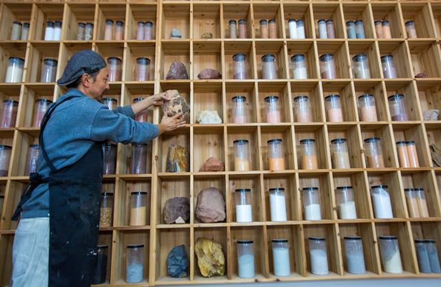 (251223) -- WUYISHAN, Dec. 23, 2025 (Xinhua) -- An artist arranges the rock pigment materials in Wuyishan City, southeast China's Fujian Province, Dec. 22, 2025. Wuyishan boasts a wide range of colorful rock and soil, which serve as a natural palette for painting, giving rise to the distinctive Wuyi rock pigment art. Integrating modern artistic elements and techniques into tradition, Wuyi rock pigment painting is gradually becoming a unique cultural feature of Wuyishan. (Photo by Chen Ying/Xinhua)