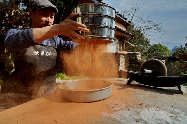 (251223) -- WUYISHAN, Dec. 23, 2025 (Xinhua) -- An artist sieves rock and soil powder in Wuyishan City, southeast China's Fujian Province, Dec. 19, 2025. Wuyishan boasts a wide range of colorful rock and soil, which serve as a natural palette for painting, giving rise to the distinctive Wuyi rock pigment art. Integrating modern artistic elements and techniques into tradition, Wuyi rock pigment painting is gradually becoming a unique cultural feature of Wuyishan. (Photo by Chen Ying/Xinhua)