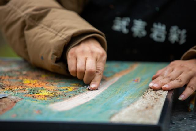 (251223) -- WUYISHAN, Dec. 23, 2025 (Xinhua) -- An artist works on a piece of rock pigment painting in Wuyishan City, southeast China's Fujian Province, Dec. 5, 2025. Wuyishan boasts a wide range of colorful rock and soil, which serve as a natural palette for painting, giving rise to the distinctive Wuyi rock pigment art. Integrating modern artistic elements and techniques into tradition, Wuyi rock pigment painting is gradually becoming a unique cultural feature of Wuyishan. (Photo by Chen Ying/Xinhua)