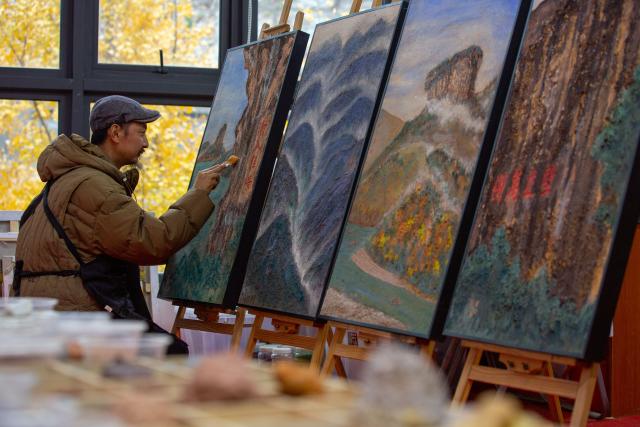 (251223) -- WUYISHAN, Dec. 23, 2025 (Xinhua) -- An artist works on a piece of rock pigment painting in Wuyishan City, southeast China's Fujian Province, Dec. 5, 2025. Wuyishan boasts a wide range of colorful rock and soil, which serve as a natural palette for painting, giving rise to the distinctive Wuyi rock pigment art. Integrating modern artistic elements and techniques into tradition, Wuyi rock pigment painting is gradually becoming a unique cultural feature of Wuyishan. (Photo by Chen Ying/Xinhua)