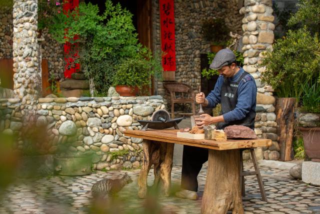(251223) -- WUYISHAN, Dec. 23, 2025 (Xinhua) -- An artist grinds rock and soil into powder in Wuyishan City, southeast China's Fujian Province, Dec. 19, 2025. Wuyishan boasts a wide range of colorful rock and soil, which serve as a natural palette for painting, giving rise to the distinctive Wuyi rock pigment art. Integrating modern artistic elements and techniques into tradition, Wuyi rock pigment painting is gradually becoming a unique cultural feature of Wuyishan. (Photo by Chen Ying/Xinhua)