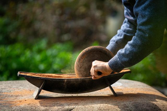 (251223) -- WUYISHAN, Dec. 23, 2025 (Xinhua) -- An artist grinds rock and soil into powder in Wuyishan City, southeast China's Fujian Province, Dec. 19, 2025. Wuyishan boasts a wide range of colorful rock and soil, which serve as a natural palette for painting, giving rise to the distinctive Wuyi rock pigment art. Integrating modern artistic elements and techniques into tradition, Wuyi rock pigment painting is gradually becoming a unique cultural feature of Wuyishan. (Photo by Chen Ying/Xinhua)