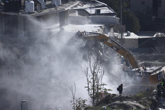 (251223) -- JERUSALEM, Dec. 23, 2025 (Xinhua) -- An excavator demolishes a residential building in the Silwan neighborhood of east Jerusalem, on Dec. 22, 2025. Israeli forces on Monday demolished a four-floor residential building in Silwan, a Palestinian neighborhood in east Jerusalem. The apartment building, home to about 90 Palestinian residents living in 13 residential units, was the largest residential structure demolished in the area this year, according to Israeli rights group Ir Amim. (Photo by Jamal Awad/Xinhua)