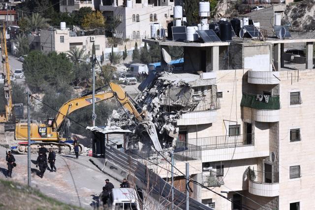(251223) -- JERUSALEM, Dec. 23, 2025 (Xinhua) -- An excavator demolishes a residential building in the Silwan neighborhood of east Jerusalem, on Dec. 22, 2025. Israeli forces on Monday demolished a four-floor residential building in Silwan, a Palestinian neighborhood in east Jerusalem. The apartment building, home to about 90 Palestinian residents living in 13 residential units, was the largest residential structure demolished in the area this year, according to Israeli rights group Ir Amim. (Photo by Jamal Awad/Xinhua)