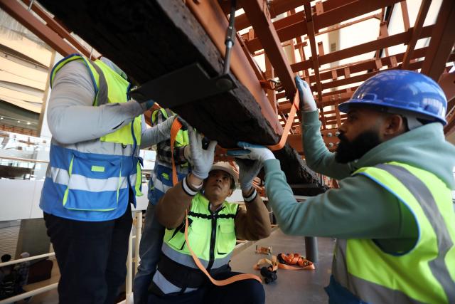 (251223) -- CAIRO, Dec. 23, 2025 (Xinhua) -- The restoration team work on the restoration project for the ancient King Khufu's second solar boat at the Grand Egyptian Museum in Cairo, Egypt, Dec. 23, 2025. Egypt on Tuesday began reassembling ancient King Khufu's second solar boat at the newly opened Grand Egyptian Museum, a restoration process expected to take about four years and open for visitors to watch live. (Xinhua/Ahmed Gomaa)