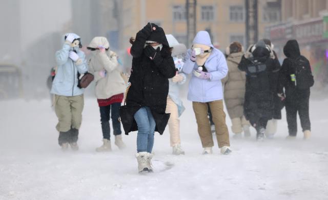 (251224) -- BEIJING, Dec. 24, 2025 (Xinhua) -- People walk on a street in snow in Harbin, northeast China's Heilongjiang Province, Dec. 23, 2025. The meteorological observatory of Harbin issued a yellow alert for blizzard on Tuesday. (Photo by Zhang Shu/Xinhua)