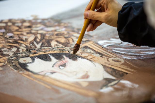 (251224) -- BEIJING, Dec. 24, 2025 (Xinhua) -- An artist works on a piece of rock pigment painting in Wuyishan City, southeast China's Fujian Province, Dec. 21, 2025. Wuyishan boasts a wide range of colorful rock and soil, which serve as a natural palette for painting, giving rise to the distinctive Wuyi rock pigment art. Integrating modern artistic elements and techniques into tradition, Wuyi rock pigment painting is gradually becoming a unique cultural feature of Wuyishan. (Photo by Chen Ying/Xinhua)
