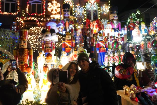 (251224) -- NEW YORK, Dec. 24, 2025 (Xinhua) -- People take selfies in front of holiday light decorations at Dyker Heights of Brooklyn in New York, the United States, Dec. 23, 2025. Residents of Dyker Heights in New York City decorated their houses with colorful lights to celebrate Christmas Day and the New Year, making their community an attraction during the holiday season. (Xinhua/Zhang Fengguo)