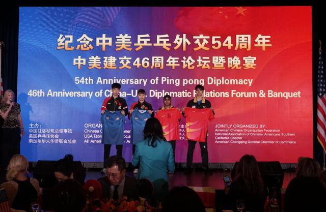 (251224) -- LOS ANGELES, Dec. 24, 2025 (Xinhua) -- Table tennis athletes from China and the United States exchange uniforms during a reception to commemorate the 54th anniversary of China-U.S. "Ping-Pong Diplomacy" in Los Angeles, the United States, Dec. 22, 2025. TO GO WITH "Legacy of 'Ping-Pong Diplomacy' highlighted at annual celebration event in Los Angeles" (Photo by Zeng Hui/Xinhua)