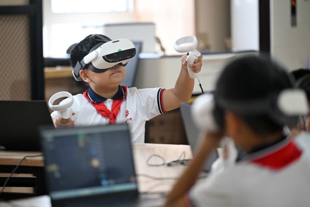 (251224) -- TIANJIN, Dec. 24, 2025 (Xinhua) -- Students experience VR equipment at an AI experience center of a primary school in north China's Tianjin, Sept. 4, 2025. TO GO WITH "Yearender-China Focus: AI takes root in basic education, nurturing future innovators" (Xinhua/Zhao Zishuo)