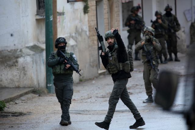 (251224) -- NABLUS, Dec. 24, 2025 (Xinhua) -- Members of Israeli forces stand guard as an Israeli bulldozer demolishes a house in the town of Bizzariya, northwest of Nablus in the West Bank, on Dec. 24, 2025. (Photo by Nidal Eshtayeh/Xinhua)