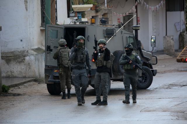 (251224) -- NABLUS, Dec. 24, 2025 (Xinhua) -- Members of Israeli forces stand guard as an Israeli bulldozer demolishes a house in the town of Bizzariya, northwest of Nablus in the West Bank, on Dec. 24, 2025. (Photo by Nidal Eshtayeh/Xinhua)
