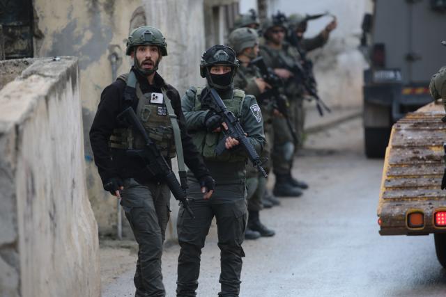 (251224) -- NABLUS, Dec. 24, 2025 (Xinhua) -- Members of Israeli forces stand guard as an Israeli bulldozer demolishes a house in the town of Bizzariya, northwest of Nablus in the West Bank, on Dec. 24, 2025. (Photo by Nidal Eshtayeh/Xinhua)