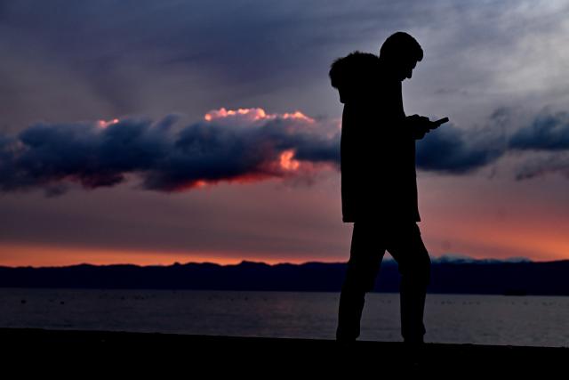 (251224) -- OHRID, Dec. 24, 2025 (Xinhua) -- A man walks on Ohrid Lake shore at sunset in Ohrid, Republic of North Macedonia, Dec. 24, 2025. (Photo by Tomislav Georgiev/Xinhua)