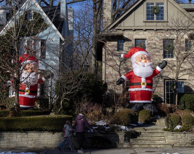 (251225) -- TORONTO, Dec. 25, 2025 (Xinhua) -- People walk past giant-sized inflatable Santa Clauses on a street in Toronto, Canada, on Dec. 24, 2025. (Photo by Zou Zheng/Xinhua)