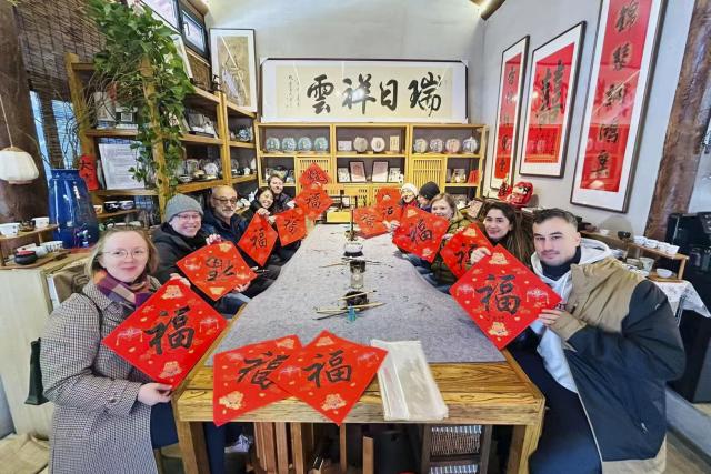 (251225) -- BEIJING, Dec. 25, 2025 (Xinhua) -- Sun Shuli's team take foreign tourists to experience Chinese calligraphy in Beijing, capital of China, in December 2025. Sun, who has worked in inbound tourism for years, now leads teams offering in-depth "citywalk" tours and cultural experiences in Beijing and Shanghai. (Xinhua)