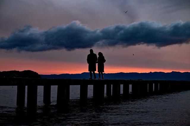 (251225) -- BEIJING, Dec. 25, 2025 (Xinhua) -- People walk on Ohrid Lake shore at sunset in Ohrid, Republic of North Macedonia, Dec. 24, 2025. (Photo by Tomislav Georgiev/Xinhua)