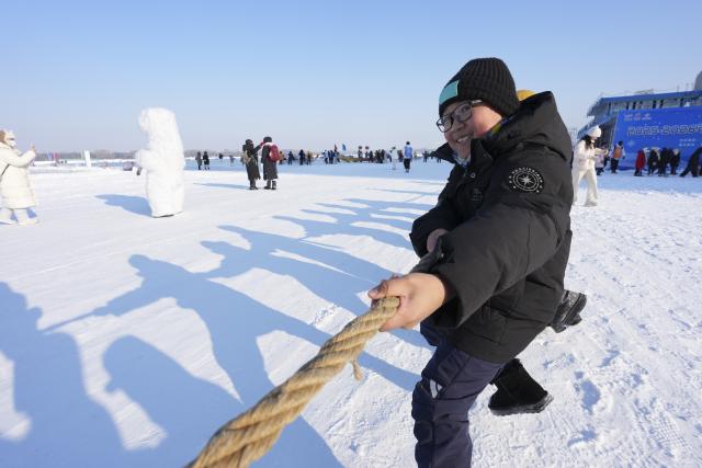(251225) -- HARBIN, Dec. 25, 2025 (Xinhua) -- A child takes part in a tug-of-war game on ice at Harbin Songhua River Ice and Snow Carnival in Harbin, northeast China's Heilongjiang Province, Dec. 25, 2025. The ice and snow carnival here kicked off on Thursday. (Xinhua/Wang Song)