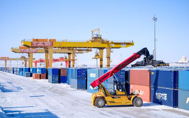 (251225) -- MANZHOULI, Dec. 25, 2025 (Xinhua) -- A crane loads containers at an international railway freight yard in Manzhouli City, north China's Inner Mongolia Autonomous Region, Dec. 24, 2025. Manzhouli City, a historic port city on the China-Russia border, has been unleashing its vigor in city development with continuously deepening of opening-up. According to data released by the Manzhouli station of exit and entry frontier inspection, the Manzhouli port has handled over 900,000 inbound and outbound passenger trips this year as of Dec. 23. (Xinhua/Ma Jinrui)