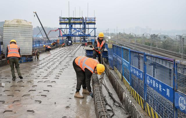 (251225) -- CHONGQING, Dec. 25, 2025 (Xinhua) -- Constructors work at the construction site of a bridge along the Chongqing-Wanzhou high-speed railway in southwest China's Chongqing Municipality, Dec. 25, 2025. Upon completion, the Chongqing-Wanzhou high-speed railway, with a designed speed of 350 km per hour, will shorten travel time from downtown Chongqing to Wanzhou District to less than one hour. (Xinhua/Chen Cheng)