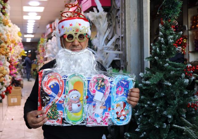 (251225) -- BAGHDAD, Dec. 25, 2025 (Xinhua) -- A man displays Christmas and New Year decorations at the Shorja market in Baghdad, Iraq, on Dec. 25, 2025. (Xinhua/Khalil Dawood)