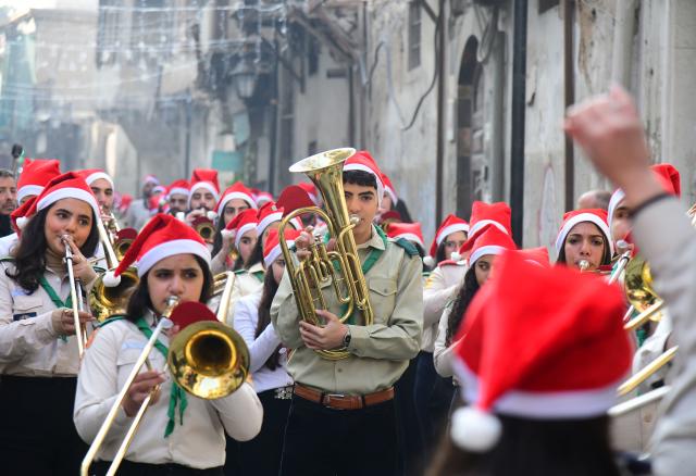 (251225) -- DAMASCUS, Dec. 25, 2025 (Xinhua) -- Members of a local scout band wearing Santa hats march through a historic street during a Christmas parade, in Damascus, Syria, Dec. 25, 2025. (Photo by Ammar Safarjalani/Xinhua)